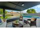 Covered patio with wicker furniture overlooks the sparkling pool and green landscaping at 8701 E Sage Dr, Scottsdale, AZ 85250