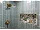 A beautiful glass shower featuring designer gold fixtures, vertical tiling, and custom rock tile niche at 8701 E Sage Dr, Scottsdale, AZ 85250