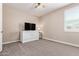 Bedroom with neutral walls, carpet, ceiling fan, and a white media center and TV at 9764 E Radioactive Dr, Mesa, AZ 85212