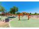 Outdoor playground area with arch-shaped play structures surrounded by green turf and trees on a sunny day at 9764 E Radioactive Dr, Mesa, AZ 85212