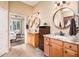 Bright bathroom featuring double sinks, granite countertops, wooden cabinets, and an open doorway to the adjacent room at 12928 W Santa Ynez Dr, Sun City West, AZ 85375