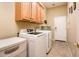 Well-lit laundry room with modern washer and dryer units, overhead cabinets, and tiled floors at 12928 W Santa Ynez Dr, Sun City West, AZ 85375