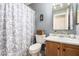 A full bath featuring a vanity, toilet, patterned shower curtain, and a framed mirror at 13359 W Post Dr, Surprise, AZ 85374