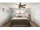 A well-lit bedroom with a ceiling fan, a plush bed with decorative pillows, and neutral-toned walls at 13359 W Post Dr, Surprise, AZ 85374