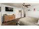 A tidy bedroom showing a dresser, TV, a ceiling fan, with neutral colors, and wall art at 13359 W Post Dr, Surprise, AZ 85374