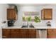 A kitchen featuring wooden cabinets, stainless steel dishwasher, and a bright window offering a pleasant view at 13359 W Post Dr, Surprise, AZ 85374