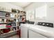 The laundry area is equipped with modern machines and storage shelves, for efficiency and organization at 13359 W Post Dr, Surprise, AZ 85374