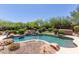 Backyard pool with rock waterfall and spa, surrounded by lush landscaping at 14619 E Desert Vista Trl, Scottsdale, AZ 85262