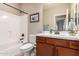 Well-lit bathroom with a shower-tub combo, a single sink vanity, and wood-stained cabinets providing ample storage at 17907 W Cedarwood Ln, Goodyear, AZ 85338