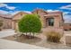 Single story home boasting well manicured landscaping including a round shrub, river rock, and a red tile roof at 17907 W Cedarwood Ln, Goodyear, AZ 85338