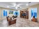 Inviting living room with tile flooring, a ceiling fan, and a custom built-in entertainment center, and a wall of windows at 19414 W Pasadena Ave, Litchfield Park, AZ 85340