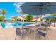 Enjoy the community pool with ample seating, umbrellas, and palm trees under a blue sky at 20642 N 268Th Dr, Buckeye, AZ 85396