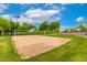Outdoor sand volleyball court surrounded by lush green grass and mature trees under a bright, sunny sky at 20642 N 268Th Dr, Buckeye, AZ 85396