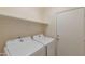 Bright laundry room with side-by-side white machines, open shelf, and a utility closet at 2312 E Williams Dr, Phoenix, AZ 85024