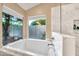 Bathroom with marble tub, shower, and a large window with backyard views at 3440 E Topeka Dr, Phoenix, AZ 85050