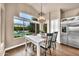 Bright dining room with large windows offering stunning backyard pool views, stainless steel fridge, and white cabinetry at 3440 E Topeka Dr, Phoenix, AZ 85050