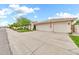Three-car garage with a large concrete driveway and walkway lined with trees at 3440 E Topeka Dr, Phoenix, AZ 85050
