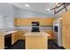 Bright kitchen with stainless steel refrigerator, wood cabinets, black appliances, marble-look countertops and island at 35656 N Shorthorn Trl, San Tan Valley, AZ 85143