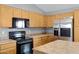 Close-up of kitchen featuring wood cabinets, stainless steel refrigerator, black appliances and marble-look countertops at 35656 N Shorthorn Trl, San Tan Valley, AZ 85143
