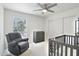 Neutral Bedroom featuring crib, plush chair, changing table, ceiling fan, and natural light at 5119 E Shaw Butte Dr, Scottsdale, AZ 85254