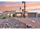 Inviting exterior view of a single-story home with desert landscaping and a palm tree at sunset at 5119 E Shaw Butte Dr, Scottsdale, AZ 85254