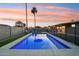 Twilight view of pool with clear blue water, a safety fence, green grass and a colorful sky at 5119 E Shaw Butte Dr, Scottsdale, AZ 85254