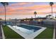 Twilight view of pool with clear blue water, a safety fence, green grass and a colorful sky at 5119 E Shaw Butte Dr, Scottsdale, AZ 85254