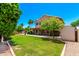 Charming landscaped backyard with lush green lawn and trees surrounding the house at 5216 W Oraibi Dr, Glendale, AZ 85308