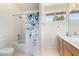 Bright bathroom featuring a shower-tub combo, white fixtures, and a single sink vanity at 5216 W Oraibi Dr, Glendale, AZ 85308