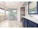 Spa-like bathroom featuring a marble shower and a navy vanity with a white marble countertop at 5216 W Oraibi Dr, Glendale, AZ 85308