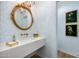 Powder room featuring a gold mirror, a luxurious marble sink, elegant wallpaper, and stylish wall decor at 5542 E Alan Ln, Paradise Valley, AZ 85253