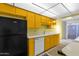 Bright kitchen features yellow cabinetry, black refrigerator, and white dishwasher at 7319 E Northland Dr # 5, Scottsdale, AZ 85251
