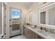 Modern bathroom featuring dual sinks, marble countertops, and designer mirrors with outside view at 9022 E Diamond Rim Dr, Scottsdale, AZ 85255
