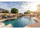 Gorgeous backyard pool with rock waterfall feature, lounge chairs, and a covered patio area for outdoor relaxation at 10617 W Daley Ln, Peoria, AZ 85383