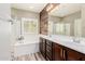 Bright bathroom featuring separate tub and shower, wood accent wall, and double vanity at 10738 W Rowel Rd, Peoria, AZ 85383