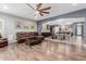 Open-concept living room features wood floors, modern fan, comfortable leather seating and direct access to the kitchen at 10738 W Rowel Rd, Peoria, AZ 85383