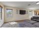Bright living room with a sectional sofa, wall-mounted TV, and charming window plants at 10923 E Flower Ave, Mesa, AZ 85208