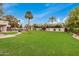 Expansive backyard featuring lush green lawn, palm trees, and a sparkling pool, perfect for outdoor enjoyment at 12821 N 67Th St, Scottsdale, AZ 85254