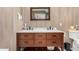 Bathroom featuring a double sink vanity with wood cabinets, marble counters, and wood-look tile walls at 12821 N 67Th St, Scottsdale, AZ 85254