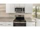 Modern kitchen with granite countertops, white cabinets, and stainless steel appliances at 12821 N 67Th St, Scottsdale, AZ 85254