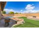 Backyard featuring a swimming pool, artificial grass, brick landscaping and block wall at 13304 W Stella Ln, Litchfield Park, AZ 85340