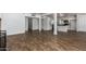 Open floor plan with wood-look tile flooring connecting living area and bright kitchen with white cabinetry at 1334 W Sells Dr, Phoenix, AZ 85013
