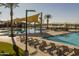Resort-style community pool and lounge area with palm trees and views to a beautiful lake, creating a relaxing atmosphere at 22980 E Raven Dr, Queen Creek, AZ 85142