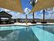 Inviting community pool area featuring shade sails, comfortable lounge chairs, and picturesque lake views, perfect for relaxation at 22980 E Raven Dr, Queen Creek, AZ 85142