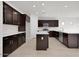 Bright kitchen features dark wood cabinetry, island with white countertop, and stainless steel appliances at 2506 N Pony Ln, Casa Grande, AZ 85122
