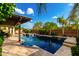 Stunning swimming pool with a pergola, built-in spa, lush landscaping, and travertine tile surround at 2851 E Alexander Ct, Gilbert, AZ 85298