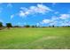 A lush green lawn offers a serene view of neighborhood homes under a clear blue sky at 36950 W Mondragone Ln, Maricopa, AZ 85138