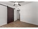 A bedroom featuring wood-look floors, a ceiling fan, barn door, and an adjacent bathroom at 3828 W Townley Ave, Phoenix, AZ 85051