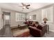 A cozy living room featuring a leather couch, decorative lighting, and shutters for privacy and light control at 41342 W Elm Dr, Maricopa, AZ 85138