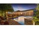 Lush backyard with a sparkling pool, ambient string lights, and inviting patio furniture at 5424 N 186Th Dr, Litchfield Park, AZ 85340